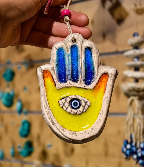 Image of lady holding a Hamsa Hand with Evil Eye Inside